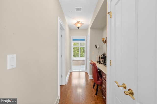 hallway with baseboards, wood finished floors, and visible vents