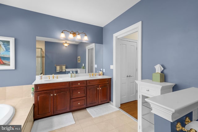 bathroom with double vanity, a sink, tile patterned floors, and a tub