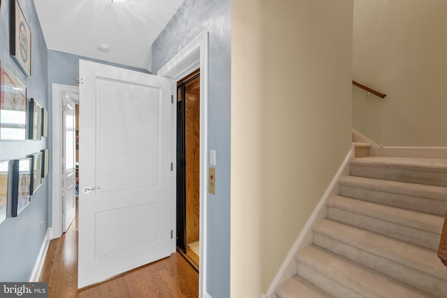 staircase featuring baseboards and wood finished floors