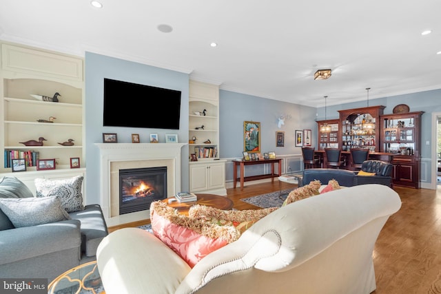 living room featuring crown molding, light wood-style floors, and built in shelves