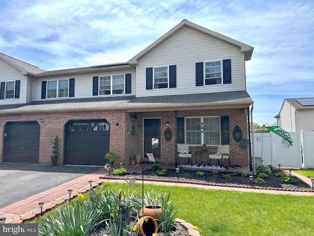 view of front facade featuring a porch, driveway, brick siding, fence, and an attached garage