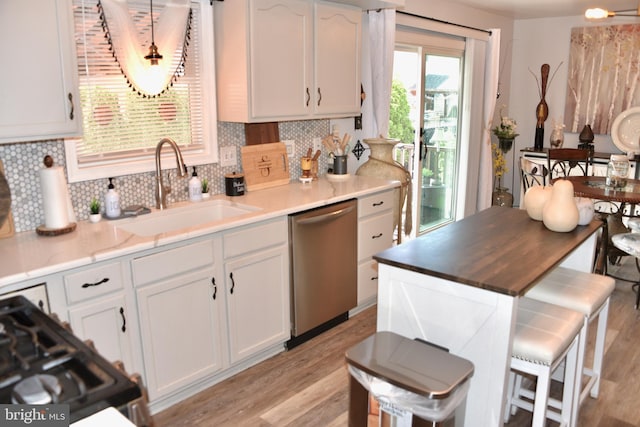 kitchen featuring decorative backsplash, white cabinets, a sink, light wood finished floors, and dishwasher