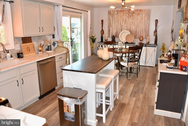 kitchen featuring tasteful backsplash, dishwasher, a sink, white cabinets, and an inviting chandelier