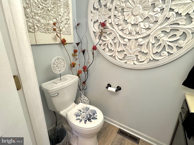 bathroom featuring visible vents, baseboards, wood finished floors, and toilet