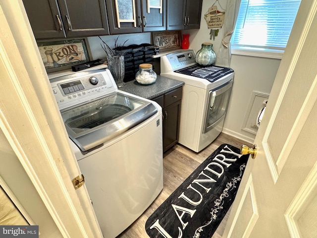 washroom featuring light wood-type flooring, cabinet space, and washing machine and dryer