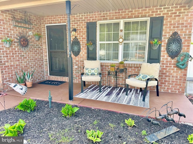 property entrance with a porch and brick siding