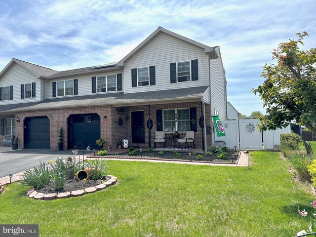 view of front of home with an attached garage, a porch, a front lawn, and brick siding