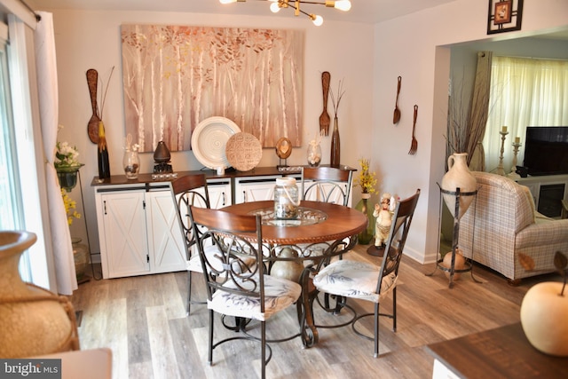 dining area with baseboards, light wood finished floors, and a notable chandelier