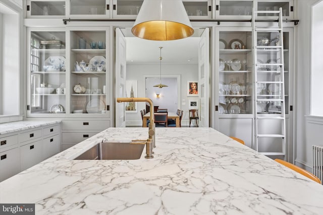 kitchen featuring a sink, light stone countertops, and glass insert cabinets