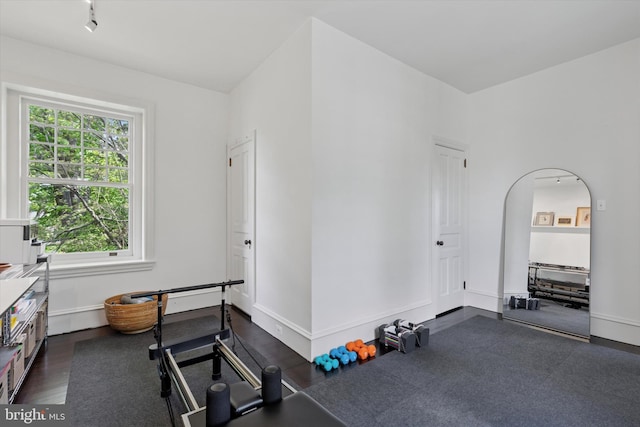 workout room featuring baseboards and dark wood-style floors