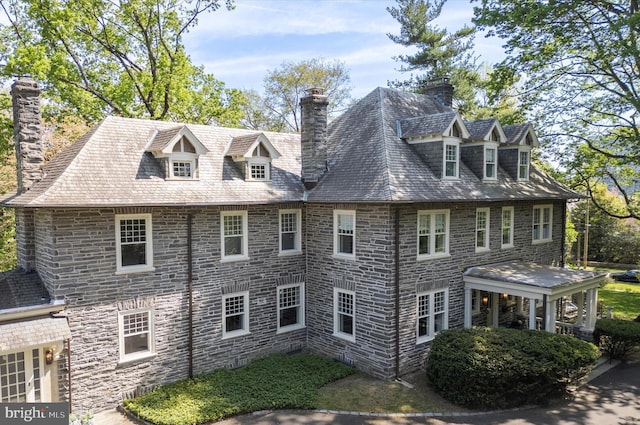 view of side of home with a chimney and stone siding
