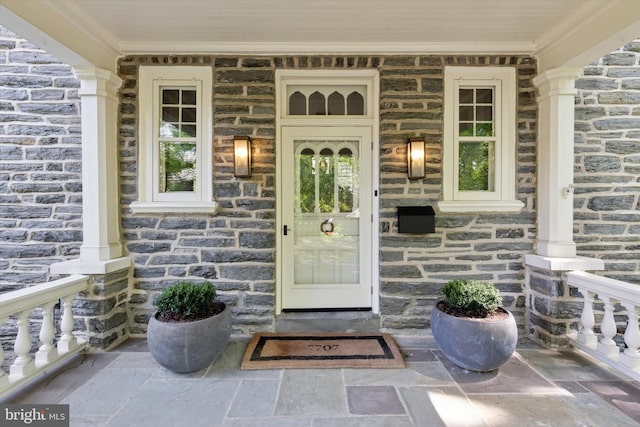 property entrance with covered porch and stone siding