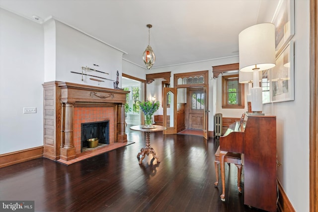 living area with baseboards, ornamental molding, a brick fireplace, and wood finished floors