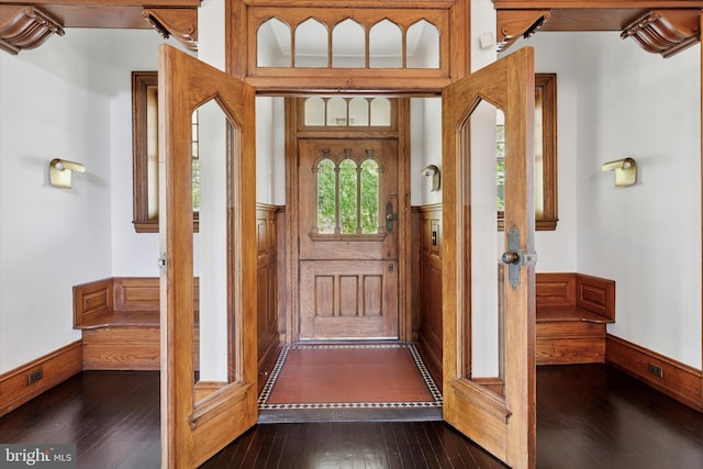 doorway with dark wood-type flooring and a wainscoted wall