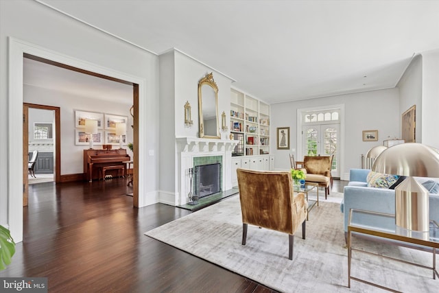 living area featuring built in shelves, baseboards, a fireplace, and wood finished floors