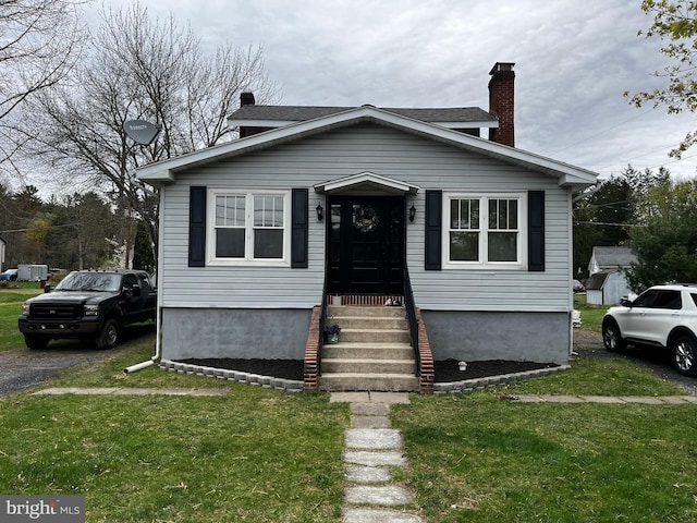 bungalow featuring a chimney and a front yard