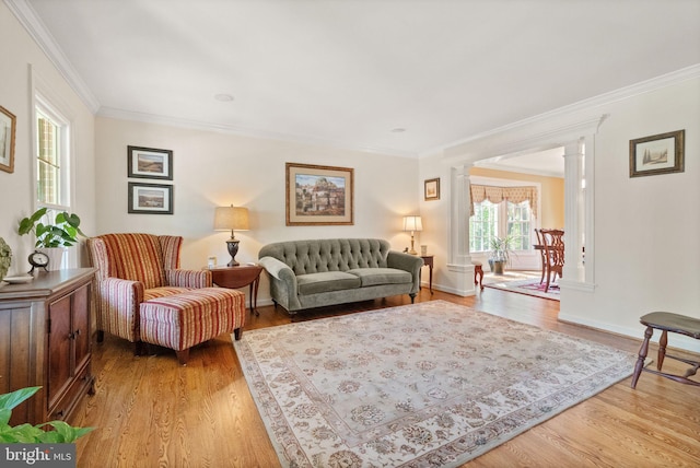 living room with crown molding, baseboards, decorative columns, and light wood-style flooring