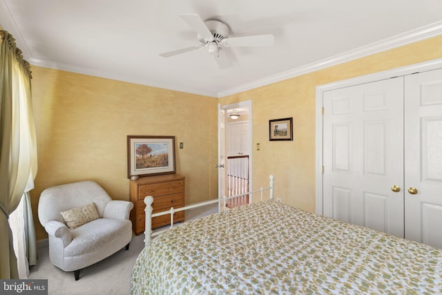 carpeted bedroom with crown molding, a ceiling fan, baseboards, and a closet