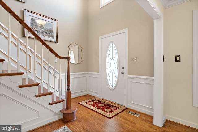 foyer featuring visible vents, wainscoting, a wealth of natural light, and wood finished floors