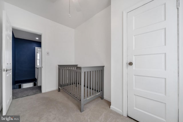 bedroom with carpet floors, baseboards, and a crib