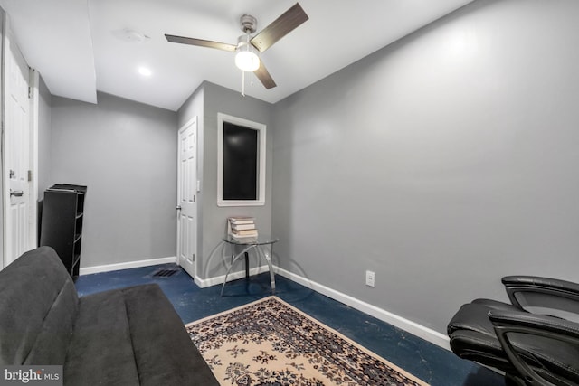 office area featuring baseboards, a ceiling fan, and concrete floors