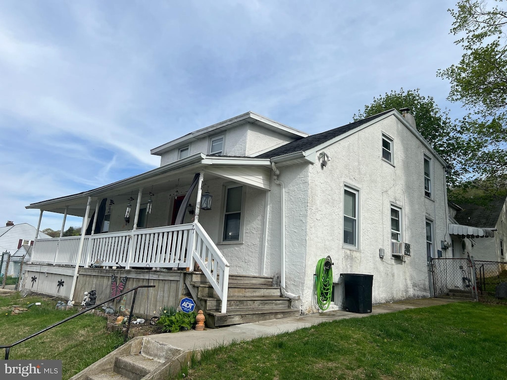 bungalow-style house featuring fence, covered porch, stucco siding, and a front lawn