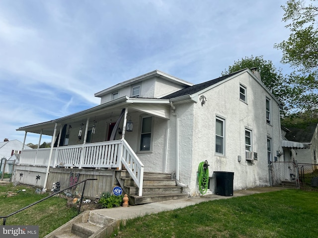bungalow-style house featuring fence, covered porch, stucco siding, and a front lawn