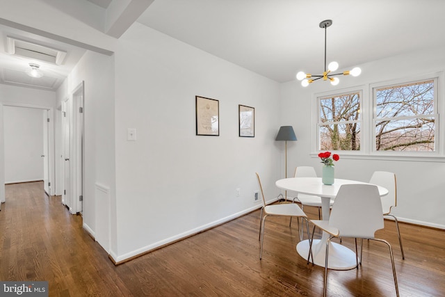 dining room with baseboards, attic access, wood finished floors, and a chandelier