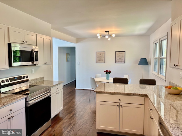 kitchen with white cabinets, dark wood-style flooring, a notable chandelier, appliances with stainless steel finishes, and a peninsula