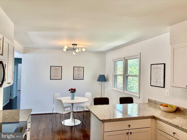 kitchen with light stone countertops, a notable chandelier, dark wood finished floors, a peninsula, and electric stove