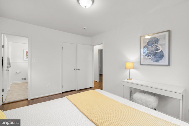 bedroom featuring baseboards, visible vents, and wood finished floors