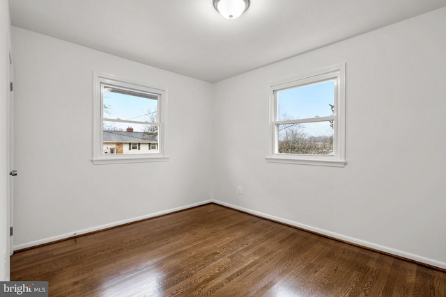 unfurnished room featuring baseboards, wood finished floors, and a healthy amount of sunlight