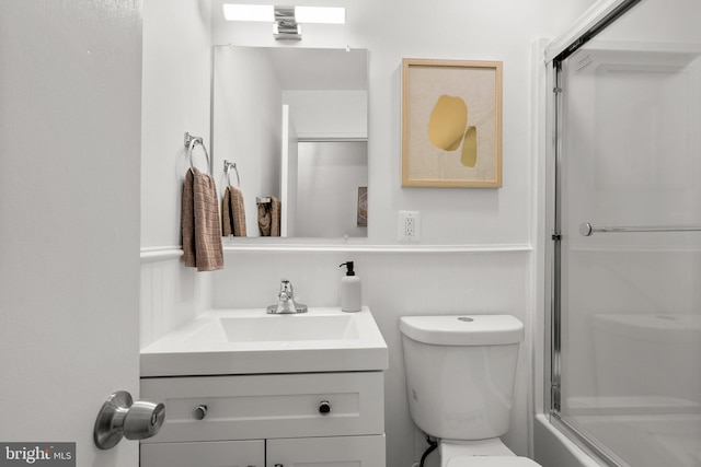 full bath with vanity, a shower with door, and toilet