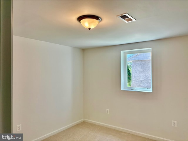 unfurnished room with baseboards, light colored carpet, and visible vents