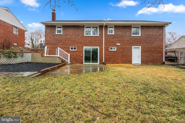 rear view of house with a lawn, a chimney, a patio area, and brick siding