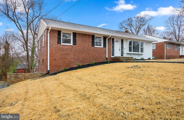 single story home featuring brick siding, a shingled roof, a chimney, and a front yard