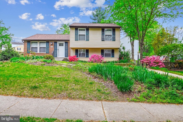 tri-level home with fence and a front lawn