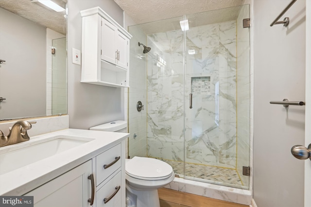 bathroom featuring a marble finish shower, vanity, toilet, and a textured ceiling