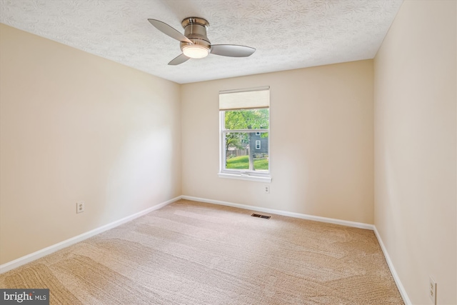 carpeted empty room with baseboards, ceiling fan, a textured ceiling, and visible vents