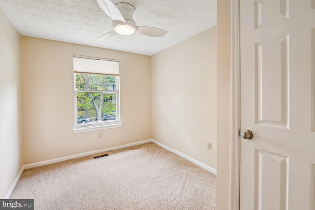 carpeted spare room featuring baseboards, ceiling fan, a textured ceiling, and visible vents