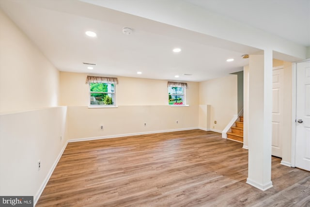 basement with baseboards, stairs, light wood-style flooring, and a wealth of natural light