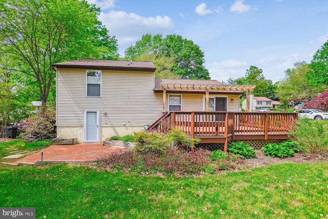 back of property featuring a lawn, a wooden deck, and a pergola