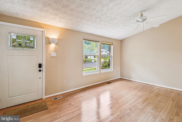 foyer entrance with a textured ceiling, baseboards, visible vents, and hardwood / wood-style floors