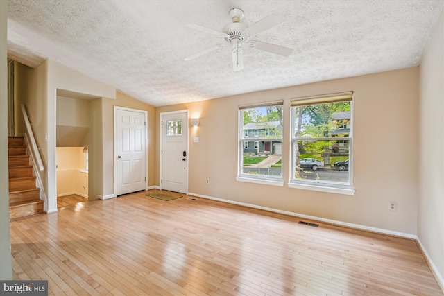 entryway featuring a textured ceiling, visible vents, light wood-type flooring, stairway, and baseboards
