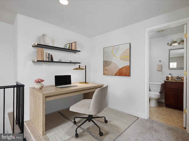 office area featuring baseboards, visible vents, light carpet, and a sink