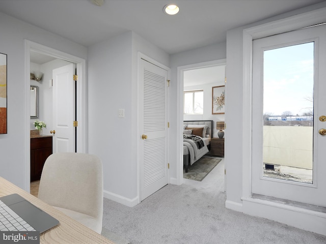 corridor with baseboards and light carpet