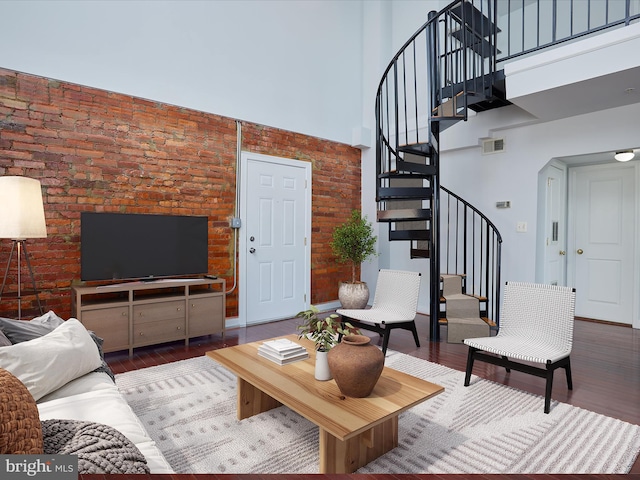 living room with arched walkways, wood finished floors, a towering ceiling, visible vents, and stairway