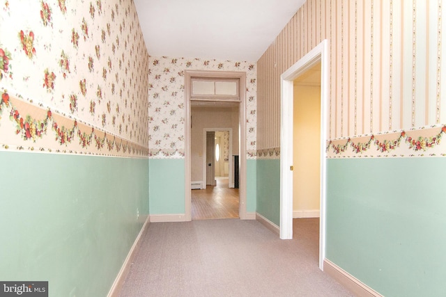 hall featuring baseboards, carpet flooring, a baseboard heating unit, and wallpapered walls