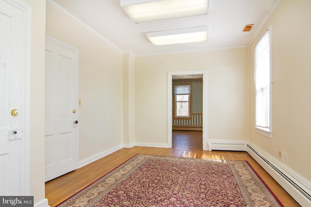 foyer with wood finished floors, baseboards, a baseboard radiator, a baseboard heating unit, and ornamental molding