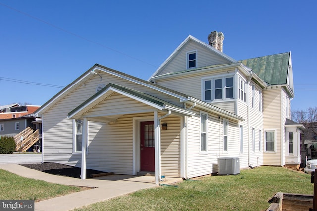 traditional-style home with a chimney, central AC, and a front yard